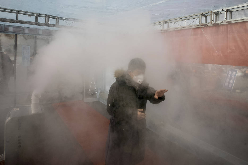 A man walks through a disinfectant spray in order to return home at a residential complex in no ...