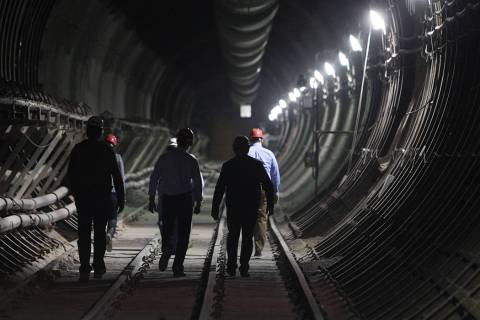 Department of Energy employees and members of the media walk toward the south portal entrance d ...