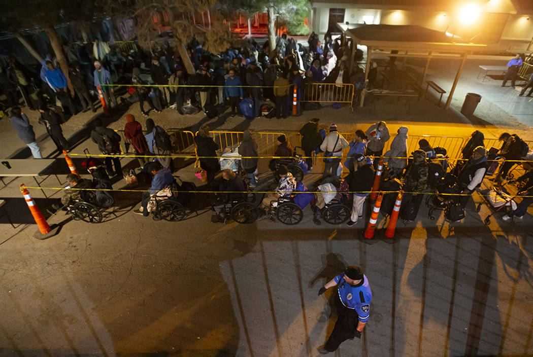 People wait in line to check in and get a sleeping mat at the Courtyard Homeless Resource Cente ...