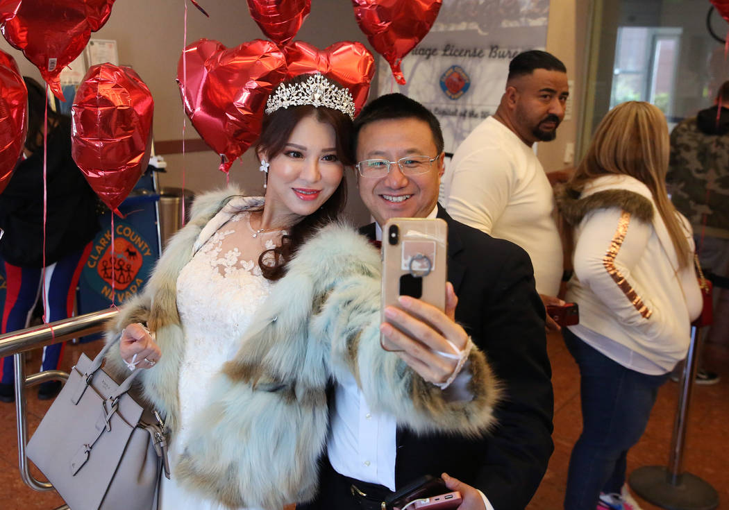 John Zhong and Catherine Li of Los Angeles pose for a selfie as they wait in line to get their ...