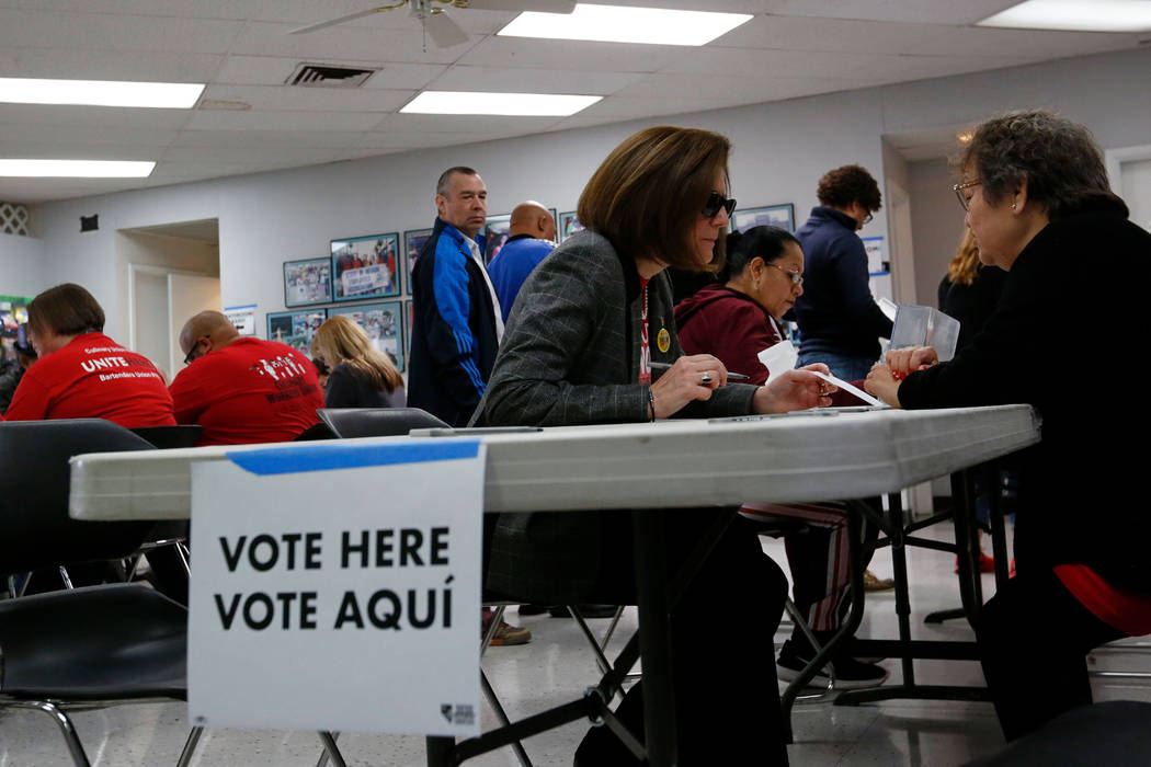 Sen. Catherine Cortez Masto, D-Nev., center fill out a paper ballot on the first day of early v ...