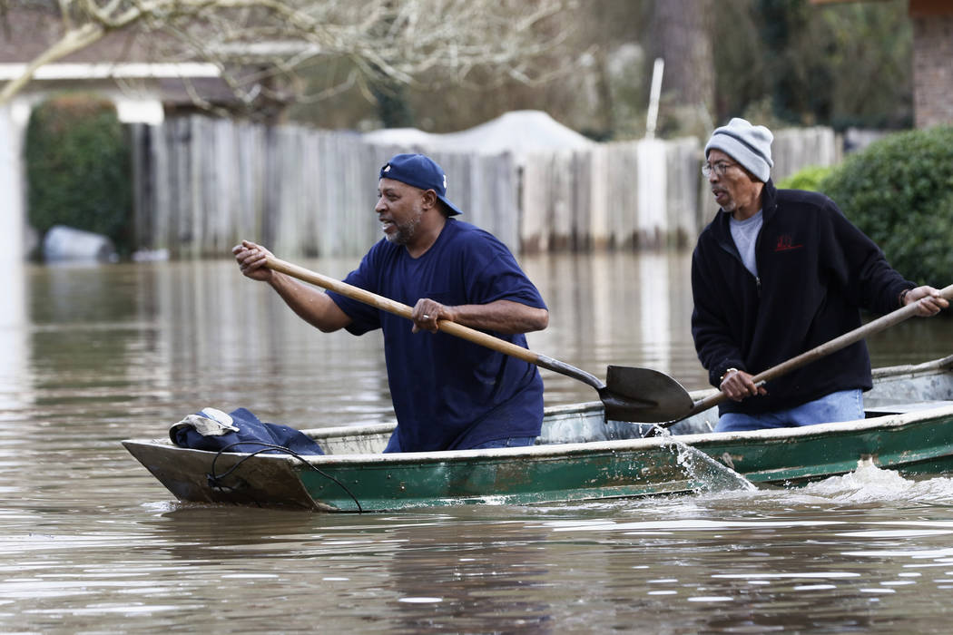 Jackson, Miss., homeowners use shovels to work their way through Pearl River floodwater in this ...