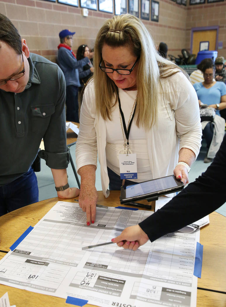 Lori Church, center, precinct chair, logs voting result on caucus math poster after Democratic ...