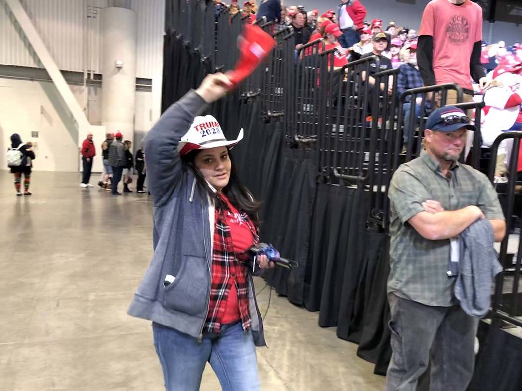 One woman waves a Trump hat while on the phone, seemingly trying to find someone in the crowd. ...