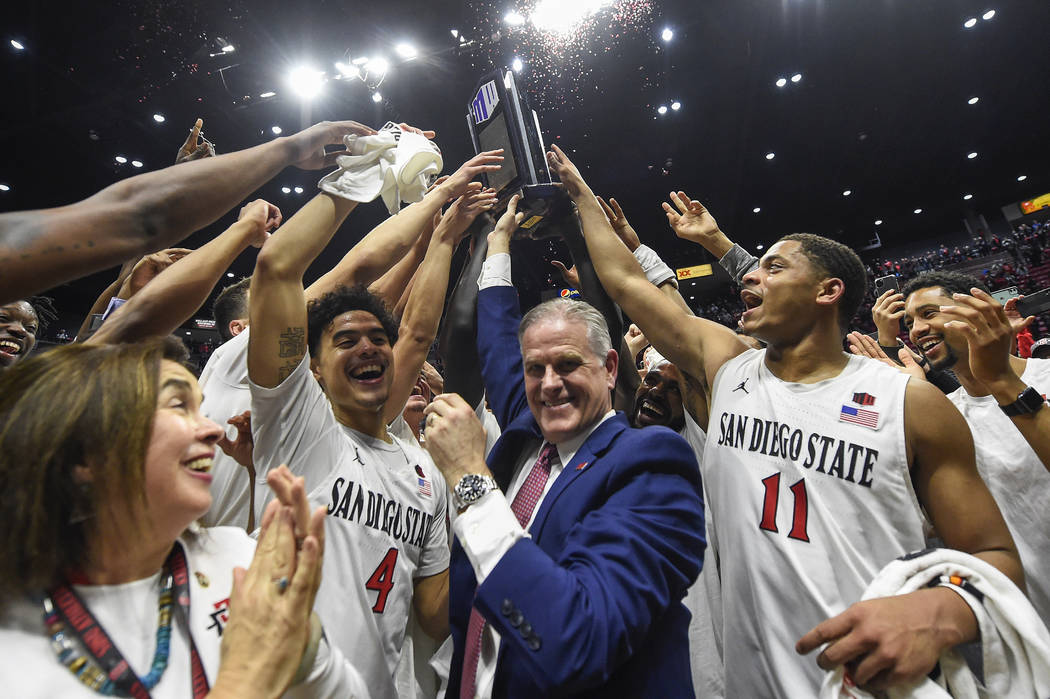 San Diego State head coach Brian Dutcher, center, and players hold up the Mountain West Champio ...