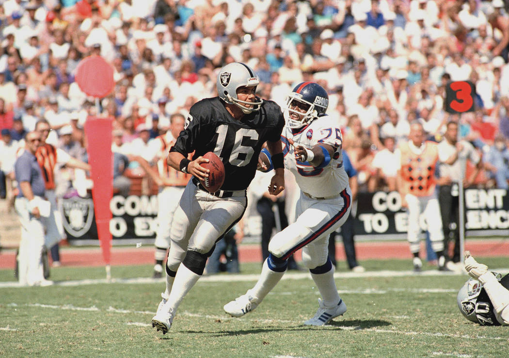 Los Angeles Raiders quarterback Jim Plunkett (16) is dogged by New York Giants George Martin du ...