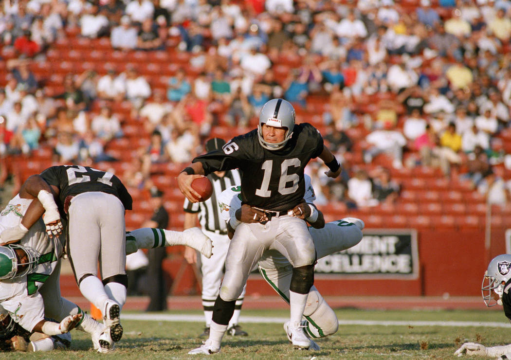 A Philadelphia Eagles player tries to drag down Los Angeles Raiders quarterback Jim Plunkett du ...