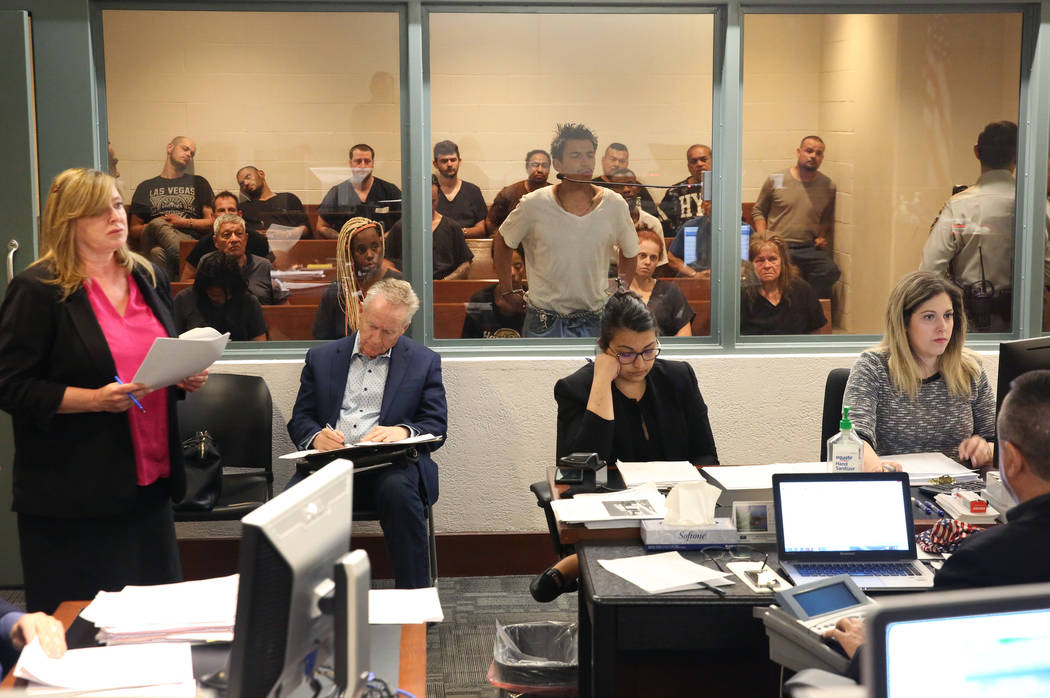 Defense attorney Leslie Park, left, addresses the court as her client, center, appears behind a ...