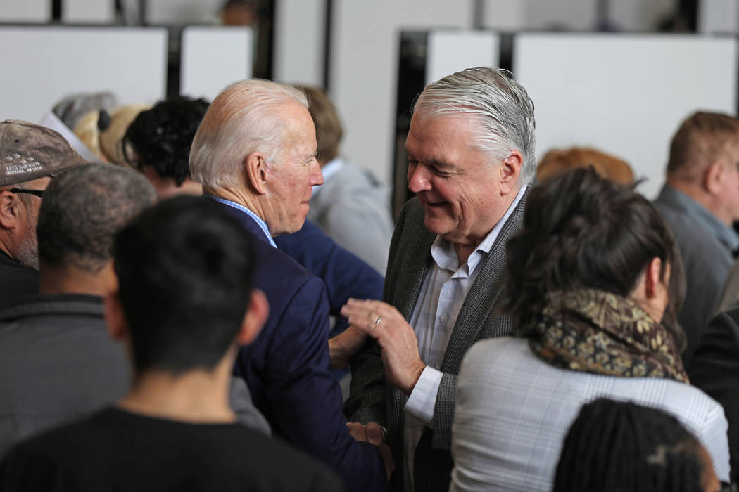 Joe Biden, left, and Nevada Gov. Steve Sisolak greet one another during caucus registration at ...