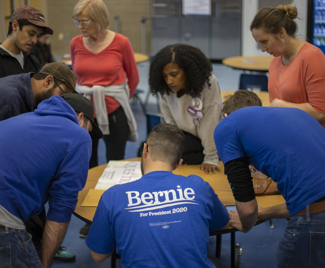 A group of Bernie Sanders supporters calculates ballots for their group during the caucus at De ...