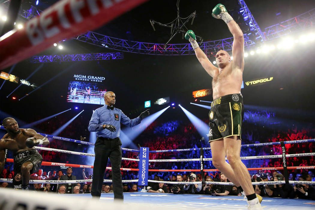 Tyson Fury, right, raises his hands after knocking down Deontay Wilder in round 3 of the WBC wo ...