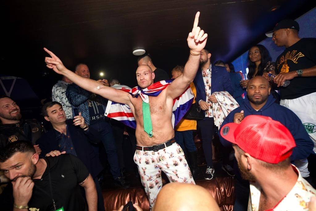 Tyson Fury (center, in green tie) is shown celebrating his seventh-round TKO victory over Deont ...