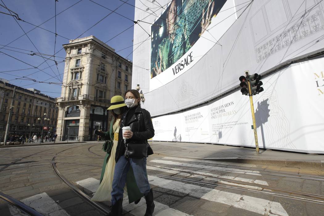 Women wearing sanitary masks walk in downtown Milan, Italy, Monday, Feb. 24, 2020. Italy has be ...