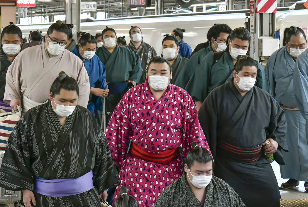 In this Sunday, Feb. 23, 2020, photo, sumo wrestlers wearing masks arrive at Shin Osaka railway ...
