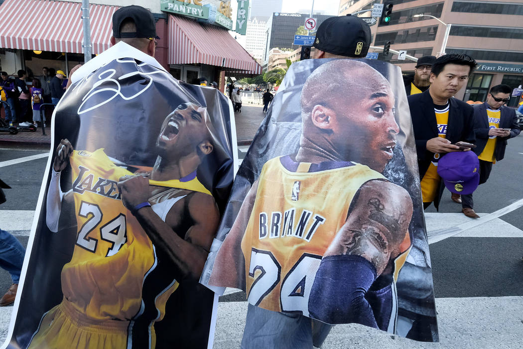 Fans carry posters of Kobe Bryant near the Staples Center before a public memorial for former L ...