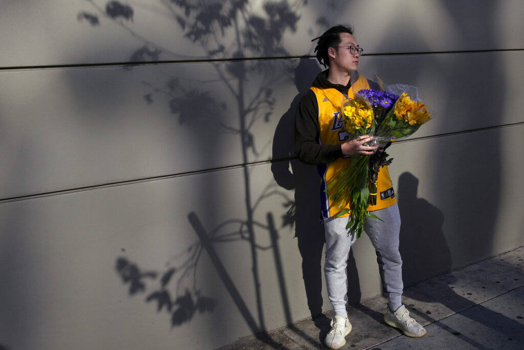 David Chen holds flowers bearing Lakers colors near the Staples Center before a public memorial ...