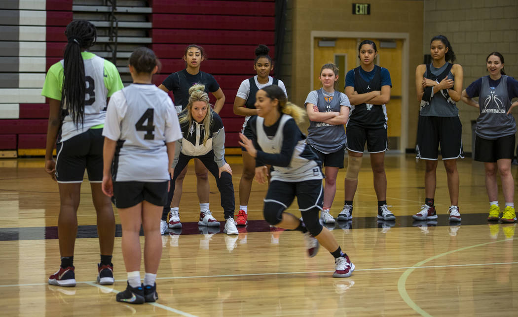 Head coach Laurie Evans, center left, looks on as her players run a play during a Desert Oasis ...