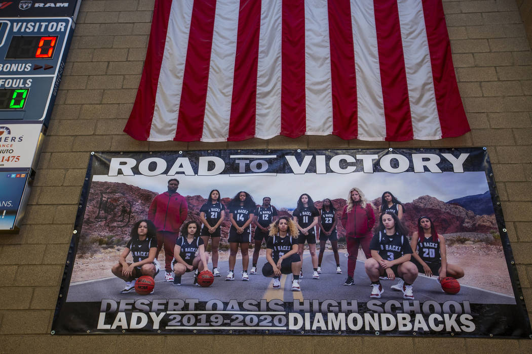 A banner hanging in the gym features the players and coaches of the Desert Oasis girl's basketb ...