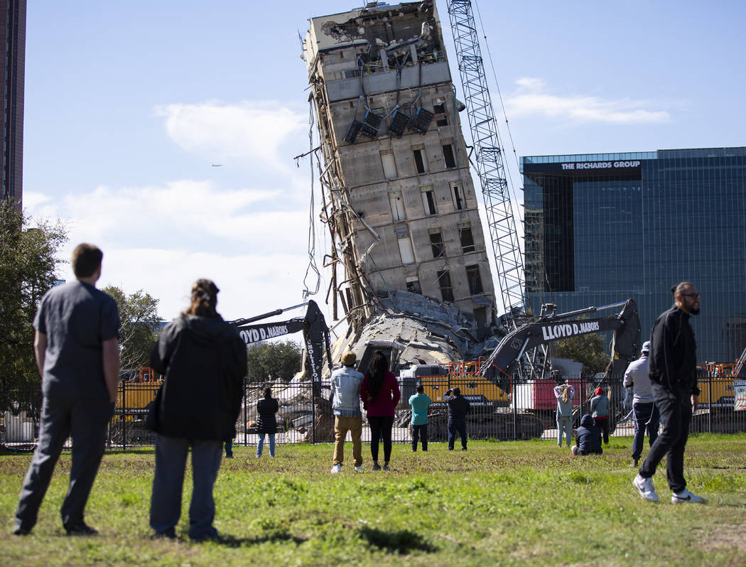 A crowd watches as Lloyd D. Nabors Demolition, LLC chips away at the top levels of the former A ...