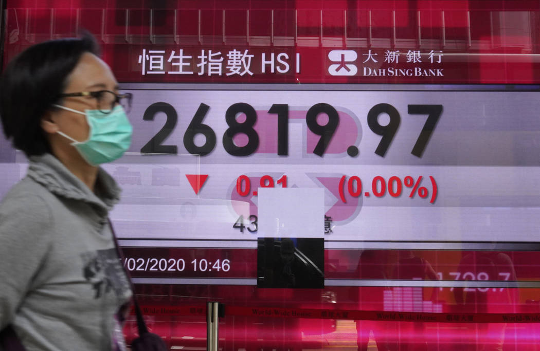 A woman walks past a bank electronic board showing the Hong Kong share index at Hong Kong Stock ...