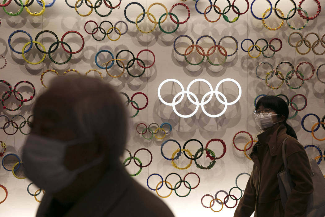 Two people wear masks as they visit the newly opened Japan Olympic Museum located near the New ...