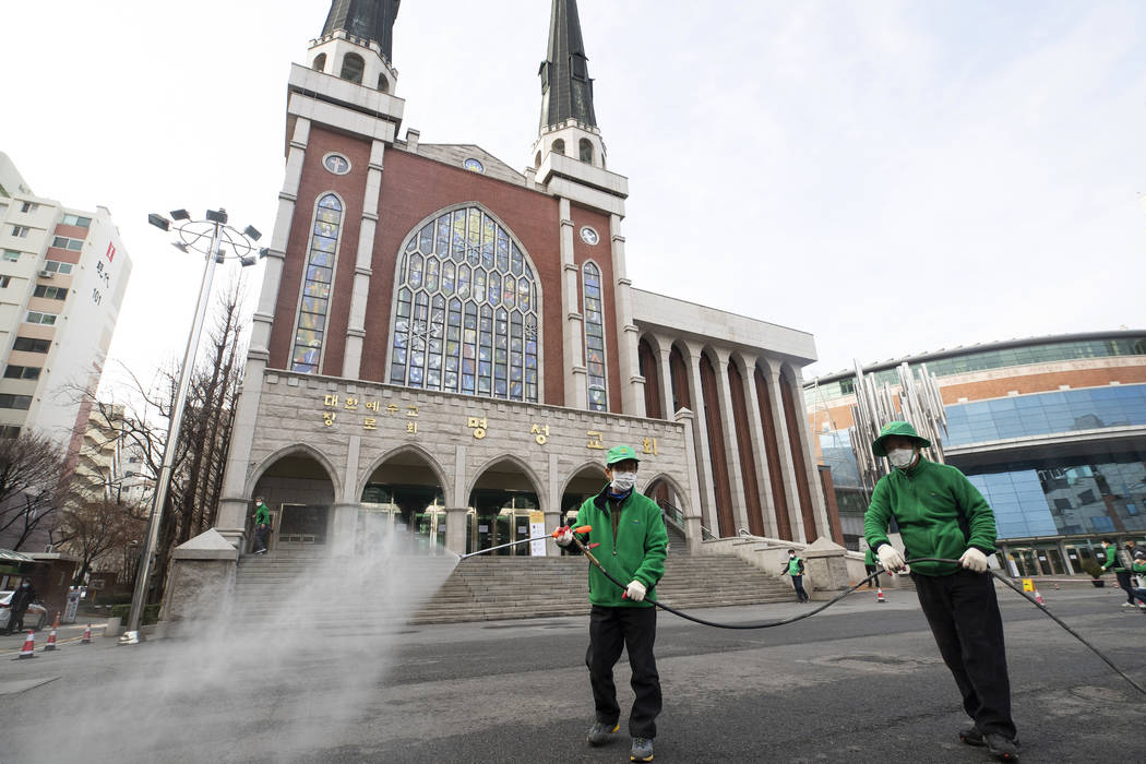 Workers wearing face masks spray disinfectant as a precaution against the new coronavirus in fr ...