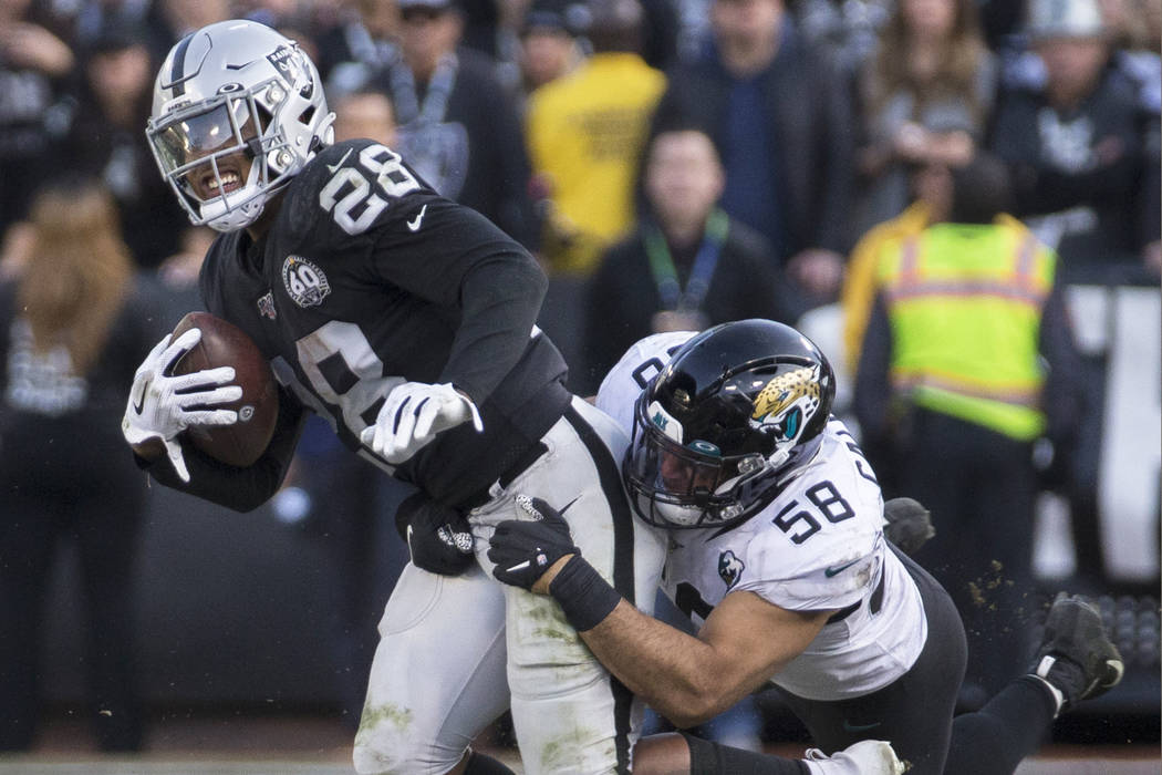 Oakland Raiders running back Josh Jacobs (28) drags Jacksonville Jaguars outside linebacker Aus ...