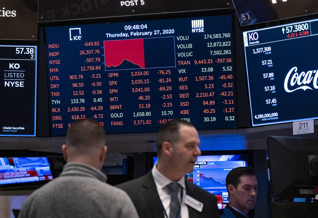 Stocks reflect declines on monitors as people work on the floor of the New York Stock Exchange ...