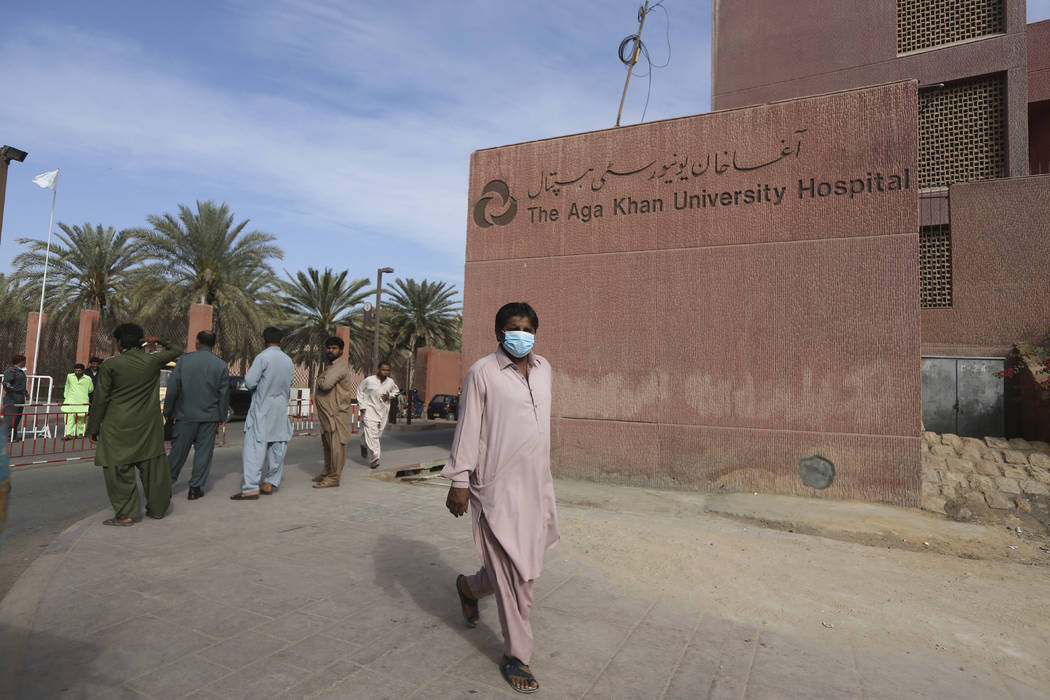 A Pakistani man wearing a face mask walks past the Aga Khan hospital where a patient suspected ...