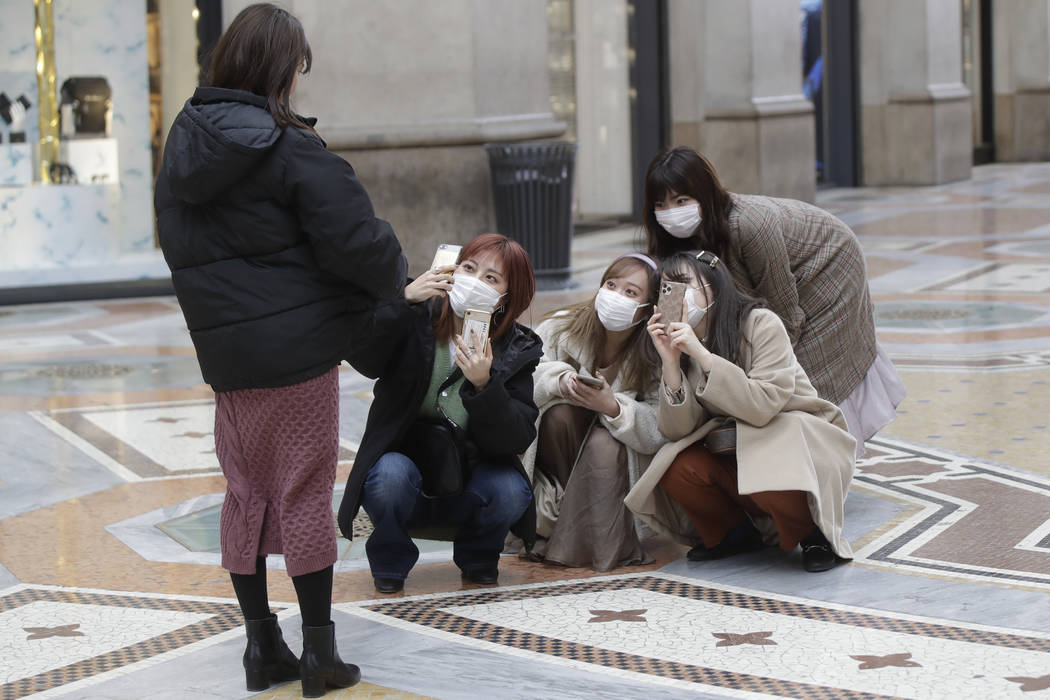 Tourists, wearing face masks, pose for a selfie in downtown Milan, Italy, Thursday, Feb. 27, 20 ...