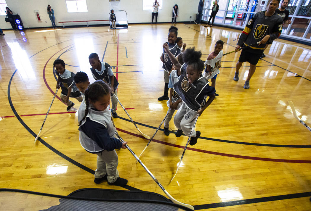 Eight-year-old Kimora Stewart, center right, celebrates after a goal during a youth street hock ...