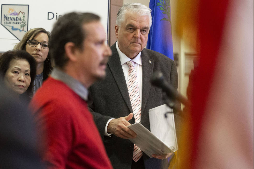 Governor Steve Sisolak, right, waits to speak during a press conference to update the public on ...