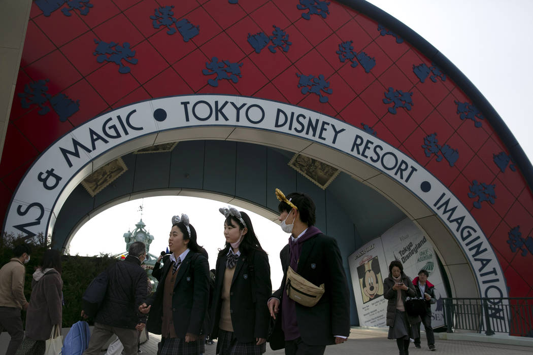 Visitors walk near the entrance to the Tokyo Disney Resort in Urayasu, near Tokyo, Friday, Feb. ...
