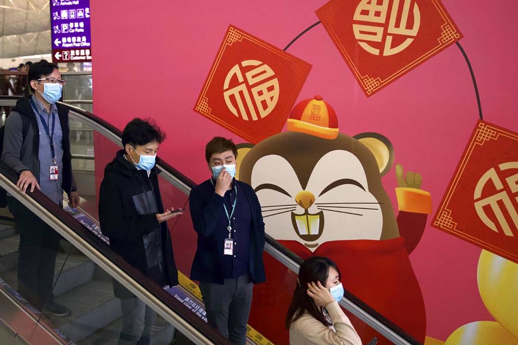 People wear face masks as they ride an escalator at the Hong Kong International Airport in Hong ...