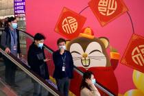 People wear face masks as they ride an escalator at the Hong Kong International Airport in Hong ...
