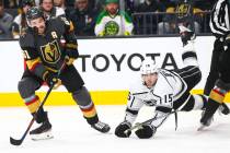 Golden Knights' Mark Stone (61) eyes the puck as Los Angeles Kings' Ben Hutton (15) gets trippe ...