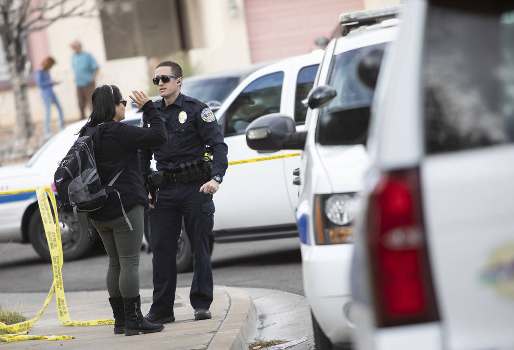 An officer speaks with a neighbor who lives near the scene of an "officer-involved" s ...