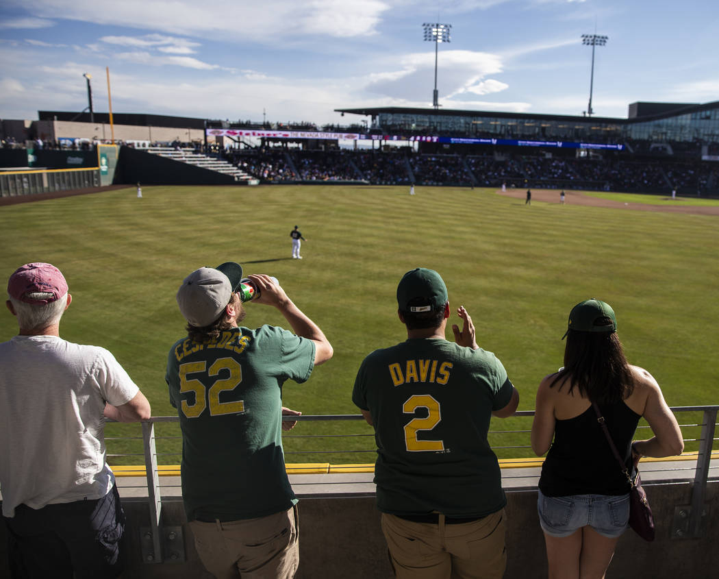 Fans watch the Cleveland Indians play the Oakland Athletics behind the center field fence durin ...