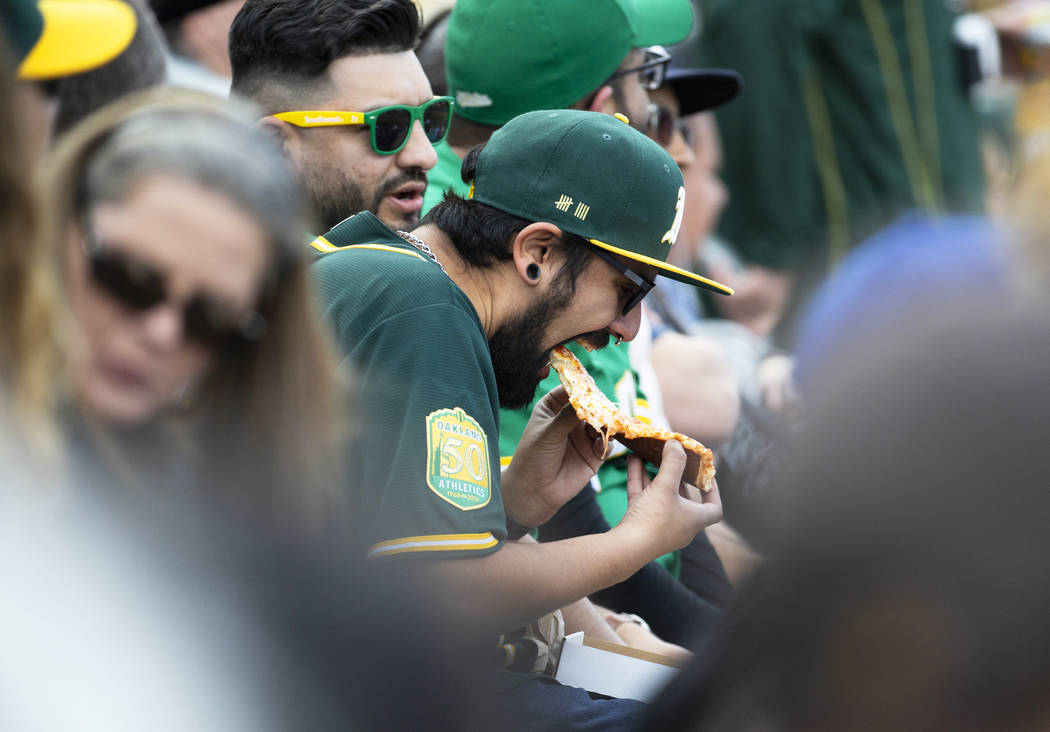 An Oakland Athletics fan enjoys a piece of pizza during a Major League Baseball game with the C ...