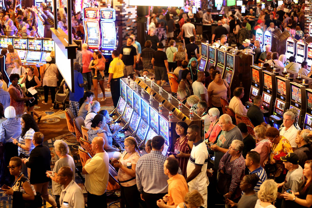 Guests line up to enroll in the M life rewards program as others play machines on opening day f ...