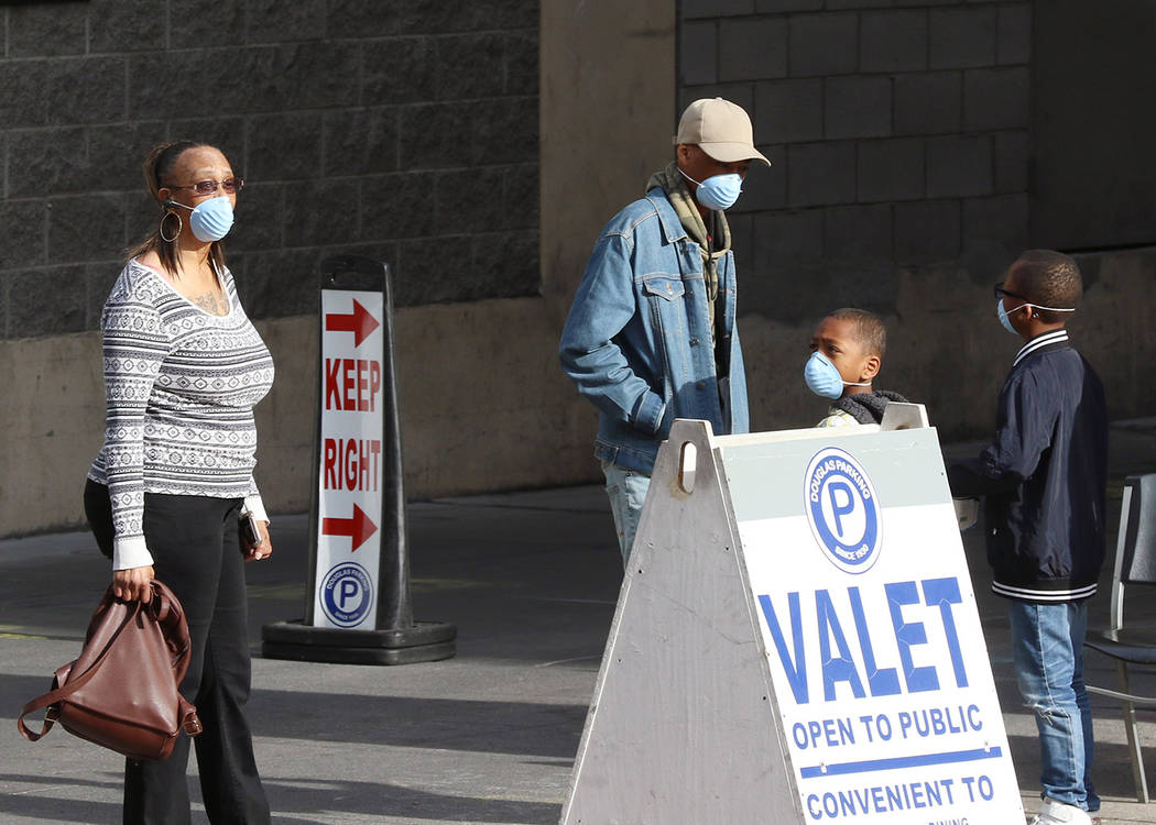 Customers wear protective masks as they wait for their vehicle at Douglas Valet Parking on Lewi ...