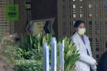 A person wearing a mask walks past a sign banning visitors at the Life Care Center in Kirkland, ...