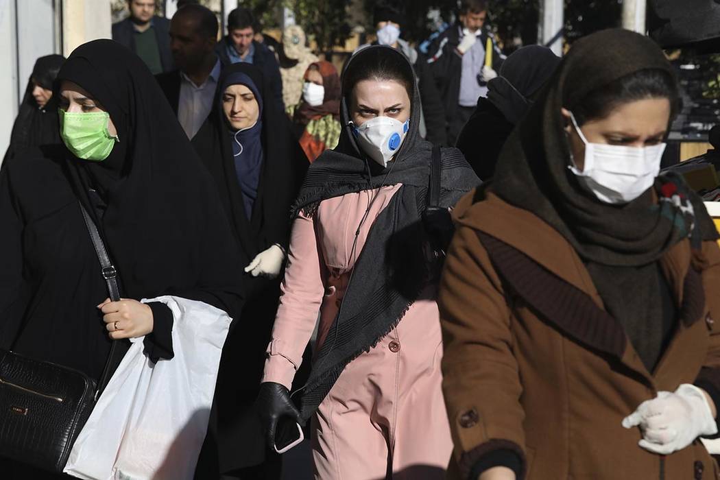 People wearing face masks walk on a sidewalk in downtown Tehran, Iran, Monday, March 2, 2020. A ...