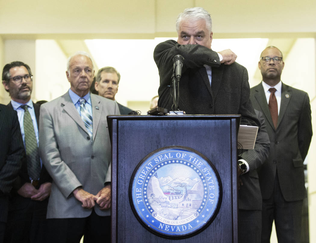Gov. Steve Sisolak demonstrates the best way to cough without spreading disease during a press ...