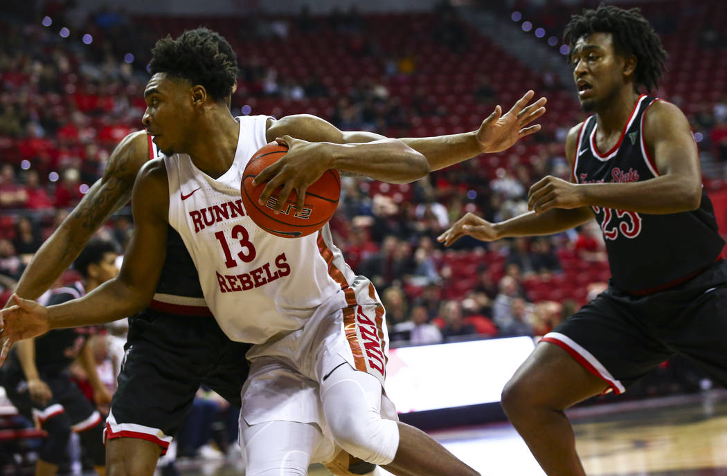 UNLV's Bryce Hamilton (13) drives to the basket past Fresno State's Anthony Holland (25) during ...