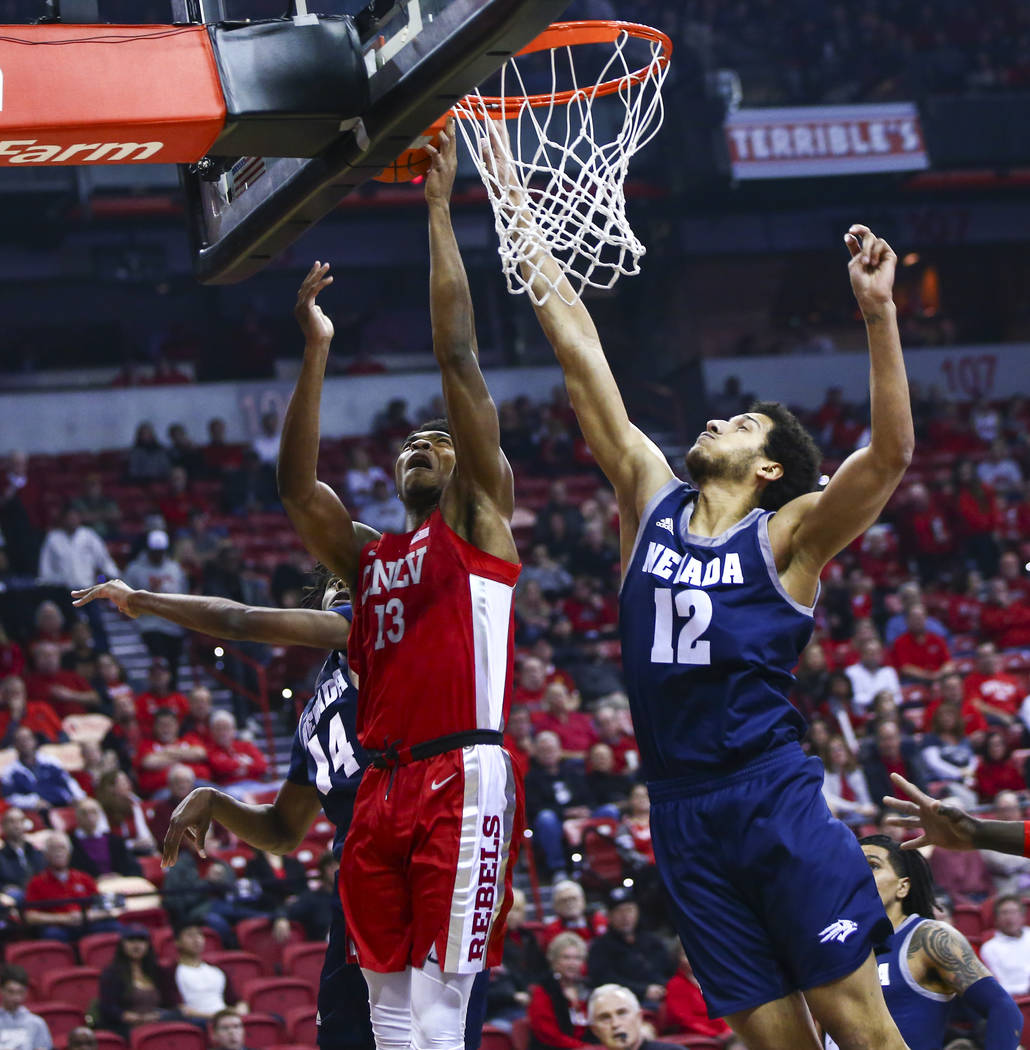 UNLV's Bryce Hamilton (13) goes to the basket against UNR's Johncarlos Reyes (12) during the fi ...
