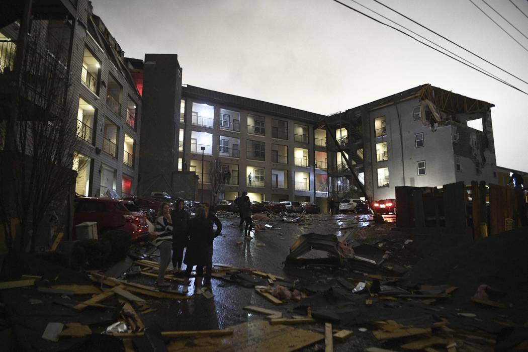 Debris is scattered across the parking lot of a damaged apartment building after a tornado hit ...