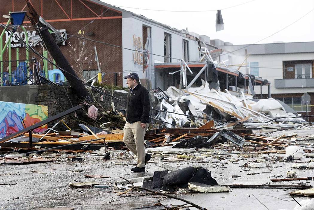 A man walks past storm debris following a deadly tornado Tuesday, March 3, 2020, in Nashville, ...