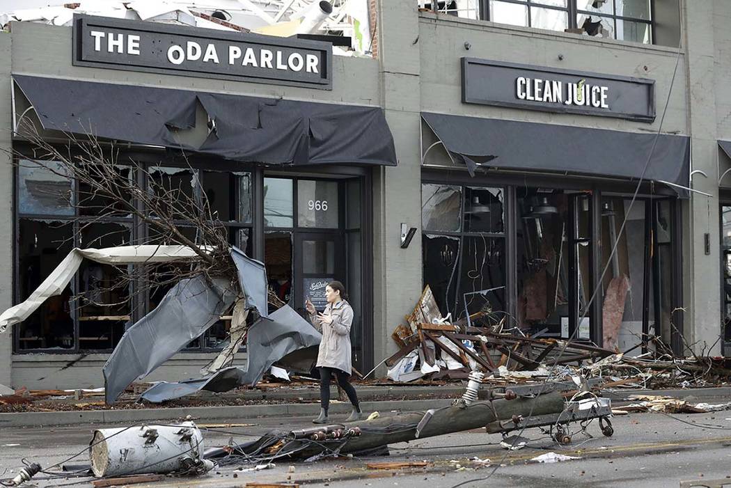 A woman walks past buildings damaged by storms Tuesday, March 3, 2020, in Nashville, Tenn. Torn ...