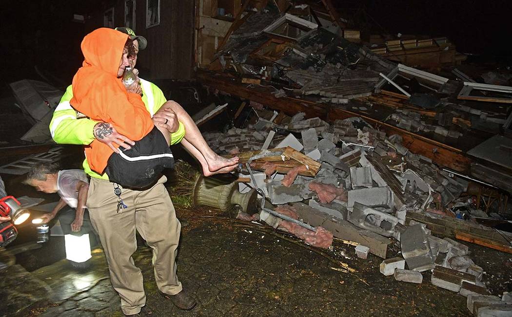 A rescue worker carries Shirley Wallace from her home that collapsed and trapped her under rubb ...
